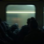 Dimly lit train carriage filled with travelers and luggage, highlighting the crowded and warm conditions of an overnight journey.
