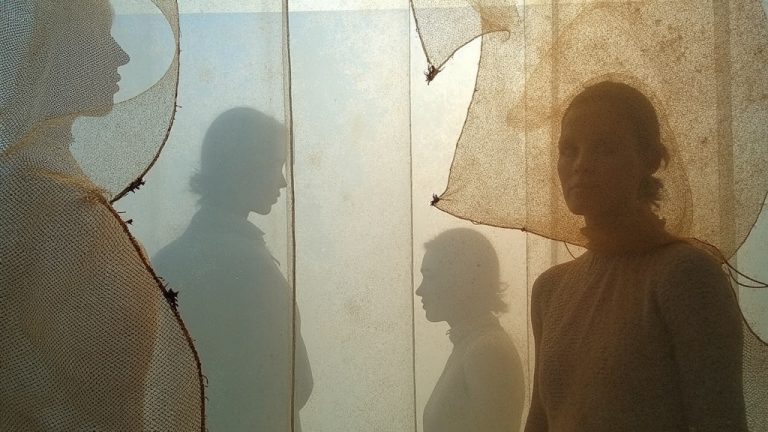 Interwoven layers of mesh and burlap with shifting light and shadow, evoking the mix of textures and temperatures travelers face in transit.