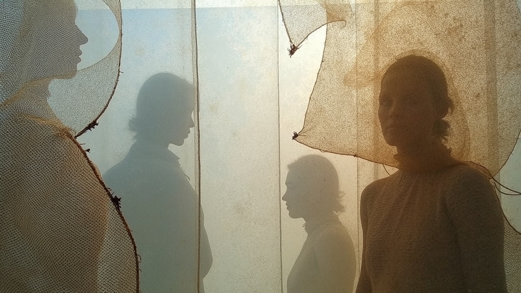 Interwoven layers of mesh and burlap with shifting light and shadow, evoking the mix of textures and temperatures travelers face in transit.